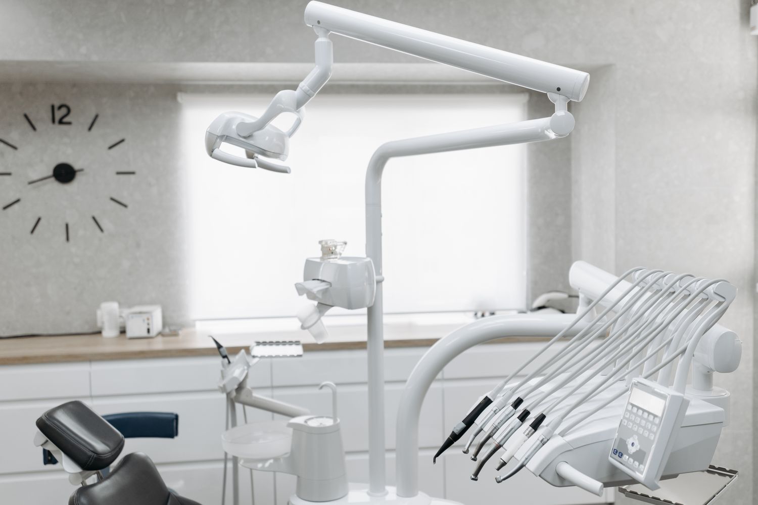 Dental unit with instruments and a lamp in a bright room.